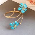 Detailed view of an elegant gold arm cuff featuring two exquisite blue enamel flowers. - Blue