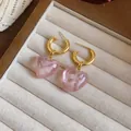 Close-up of pink marbled heart pendants on gold hoop earrings in a display tray - Earrings / Silver Needle / Pink