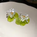 Close-up macro view of clear floral resin and green circular shell drop earrings for women - Green