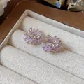 Nahaufnahme von eleganten lila Emaille-Blüten-Ohrringen mit glänzenden Zirkonia-Akzenten. - Creole-Silber-Lila
