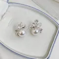 Detailed view of French style pearl and zircon stud earrings in a light blue jewelry box. - Silver Pin (Silver) / White