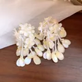Nahaufnahme von eleganten Perlenohrringen mit Blumenquasten für einen süßen Sommerurlaub. - Silber-Ohrstecker-Stil / Gelb