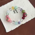 Macro detail of a colorful beaded bracelet featuring cute resin apple and peach charms. - Multicolor