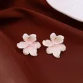 Elegant flower-shaped stud earrings with zircon center on a dark brown textured background - Style 1