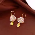 Macro detail of floral crystal earrings featuring pink zircons and large yellow teardrop pendant - Style 4