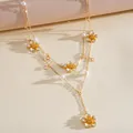 Detail view of a double-layered gold necklace with enamel flowers and pearls - Stacked Set / Gold-White