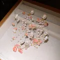 Detailed macro view of elegant pearl earrings featuring delicate pink stone tassels on gold chains - White-Pink