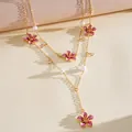 Close-up detail of a two-layer gold necklace featuring pink enamel flowers and pearls - Stacked Set / Gold-Pink