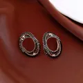 Elegant oval black zircon stud earrings with gold plating on a brown silk background. - Style 12