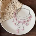 Detailansicht der mehrlagigen Halskette mit rosa Blüten und Quasten-Anhängern - Blumen-Quasten-Stil / Silber-Rosa