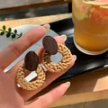 Dettaglio di orecchini a cerchio in rattan fatti a mano con decoro in legno scuro - Ago d'argento / Marrone