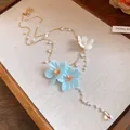Close-up detail of resort-style gold chain necklace with blue fabric flowers and pearls - Necklace Style (HN11883) / Gold & Blue