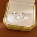 Close-up of minimalist silver needle round resin stud earrings in a green velvet jewelry box - Silver-White