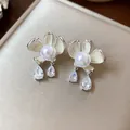 Elegant floral stud earrings featuring cream enamel petals, center pearls and drop crystals. - Silver-White