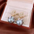 Elegant gold butterfly earrings with large grey pearls presented in a luxury gift box. - Style 32