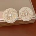 Primer plano de pendientes redondos grandes totalmente incrustados de strass brillante - Dorado