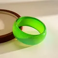 Detailed view of a vibrant green resin bangle with a sparkling glittery finish and smooth surface - Green