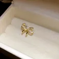Macro view of gold-tone bow ear cuff with zircons and pearl in jewelry box - Bow Pearl Style / Single Piece / Gold