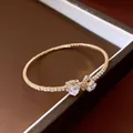 Close-up detail of a gold open heart bracelet featuring clear gemstones and pavé diamonds - Heart Open Style / Gold