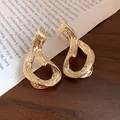 Primer plano de pendientes geométricos bañados en oro de 18k con acabado de textura - Estilo Geométrico Irregular (HE33600) / Dorado