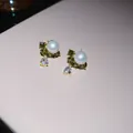 Detail van elegante pareloorbellen met groene stenen en druppelvormig kristal in goud - Parel Zirconia Waterdruppel Oorknopjes / Goud