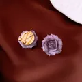 Elegant purple rose stud earrings with gold-plated backing on textured maroon fabric - Style 60
