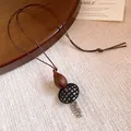 Close-up detail of a vintage ethnic style long necklace with resin wood-grain pendant. - Tassel Combination Style