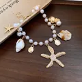 Detailansicht der Perlenkette mit Seestern- und Muschelanhängern in Gold für den Urlaub - Armband