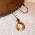 Close-up detail of a vintage ethnic style long necklace with a circular resin pendant. - Double Ring Bamboo Texture Style