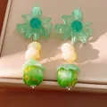 Primo piano di orecchini a fiore in resina verde con perline gialle e verde mela. - Stile Pony Geometrico Floreale / Verde