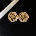 Detailed macro shot of elegant golden hollow flower earrings with shimmering yellow crystals. - Gold