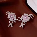 Elegant flower and bow stud earrings featuring pink zirconia crystals and central pearl - Style 71