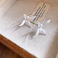 Close-up of elegant white matte flower drop earrings displayed in a vintage wooden box - White