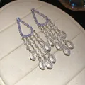 Detailed close-up of sparkling zircon tassel earrings with pearls and teardrop crystals - Dangle Earrings / Silver-White