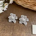 Macro view of white enamel hollow lace flower stud earrings with a central pearl - White