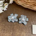 Close-up of light blue enamel flower earrings with pearl center and hollow design - Blue