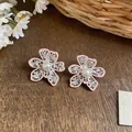 Close-up of pink enamel hollow flower earrings with intricate lace details and white pearls - Pink