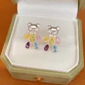 Close-up of bear-shaped stud earrings with vibrant colorful zircon stones in a gift box. - Colorful