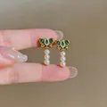 Primo piano di orecchini a farfalla vintage con smalto verde e perle. - Oro-Verde-Bianco