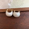 Detailed macro view of white enamel bean-shaped earrings with 18k gold plating. - Enamel Bean Style (HE10919) / Earrings - White