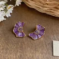 Detailed view of elegant purple enamel flower stud earrings with sparkling crystals. - Purple