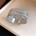 Close-up detail of an elegant silver woven metal cuff bracelet with intricate mesh design - Silver