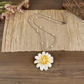 Dettaglio di una collana con ciondolo a margherita bianca e perle su stuoia rustica. - Bianco Trasparente