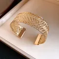 Close-up detail of vintage gold metallic woven pattern on a stylish open cuff bracelet - Gold