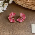 Close-up of dopamine style pink enamel flower stud earrings with red rhinestone centers - Pink