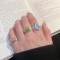 Vintage geometrische Katzenaugenstein-Ringe getragen an einer Hand vor einem Buchhintergrund - Mischstile
