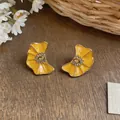 Detailed view of yellow enamel pleated flower earrings with rhinestone center - Yellow