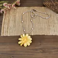 Primo piano dettagliato di una collana con pendente a margherita gialla e perle bianche. - Giallo - Trasparente
