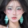 Close-up of a model wearing teal layered shell earrings with iridescent finish - Small Tiered Disk Style