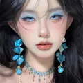 Close-up of artistic blue shell earrings and matching necklace on a model for summer. - Irregular Shell Texture